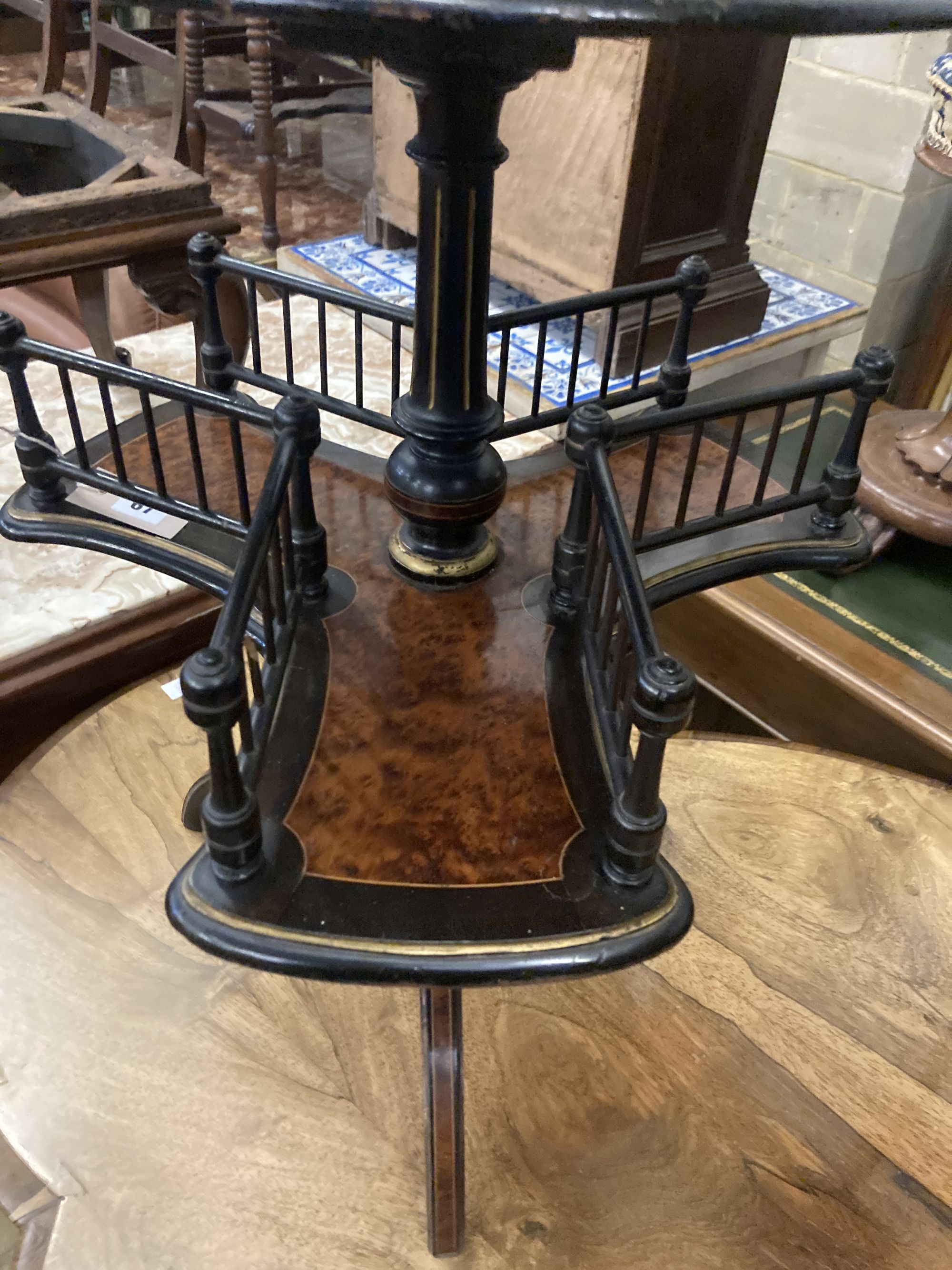 An ebonised and gilt thuya or walnut book table, the circular top over revolving trefoil book rack